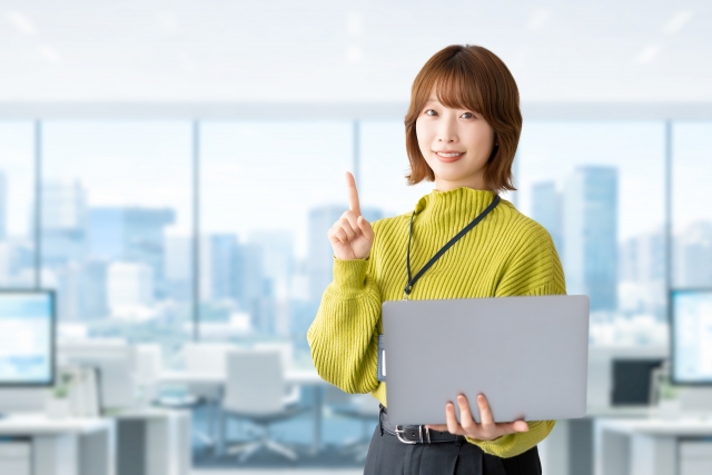 ノートパソコンを持ちながら指を立てて説明するビジネスウーマン
